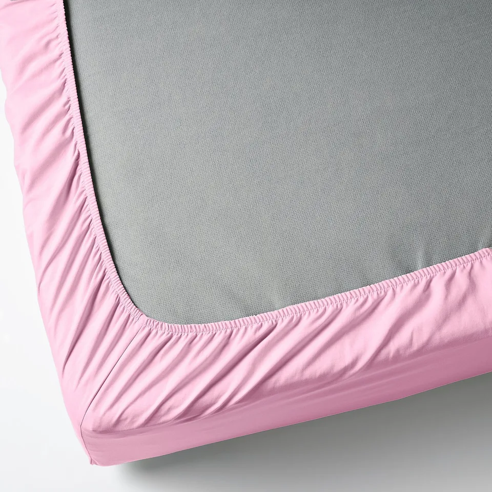 Displays a fitted sheet with a pink elastic border, designed to fit mattresses up to 26 cm thick.