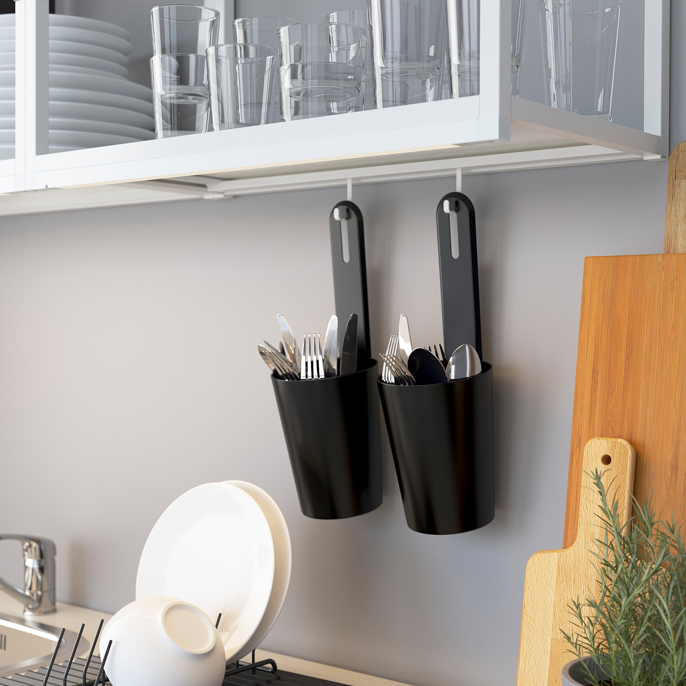 Kitchen storage with black hanging containers holding utensils. Shelf displays glassware above.