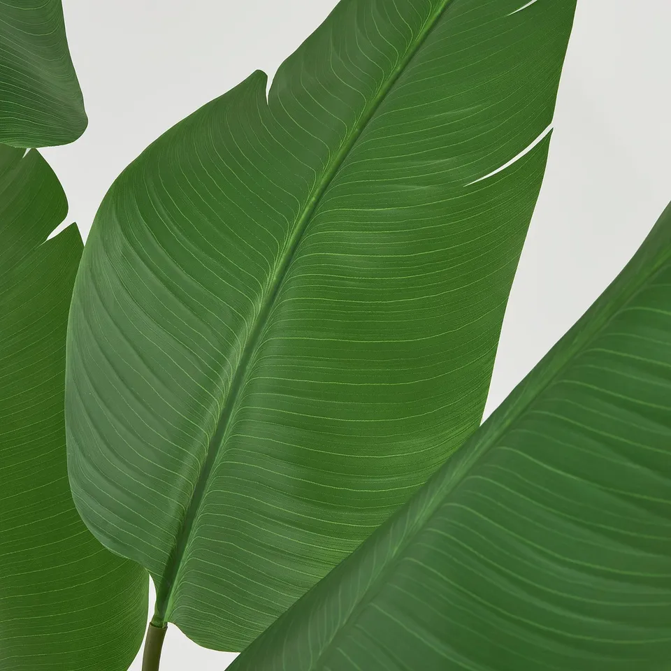 Large, vibrant green leaves of an artificial plant, detailed veining, packed neatly.