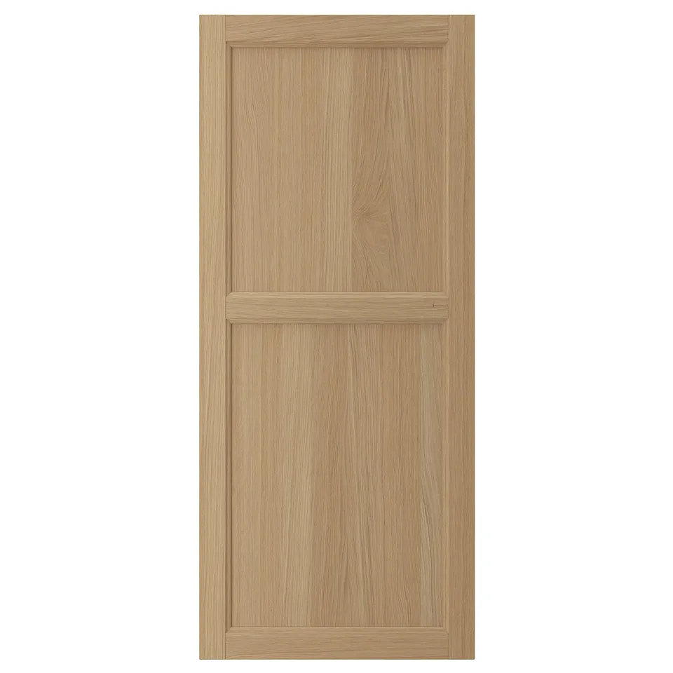 A VEDHAMN wooden door in a light oak finish. It has a solid oak frame with oak veneer panels, featuring a simple yet elegant design.