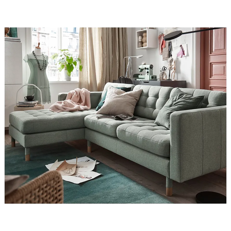 Displays a modern grey l-shaped sofa named LANDSKRONA. Its styled in a cosy living space.