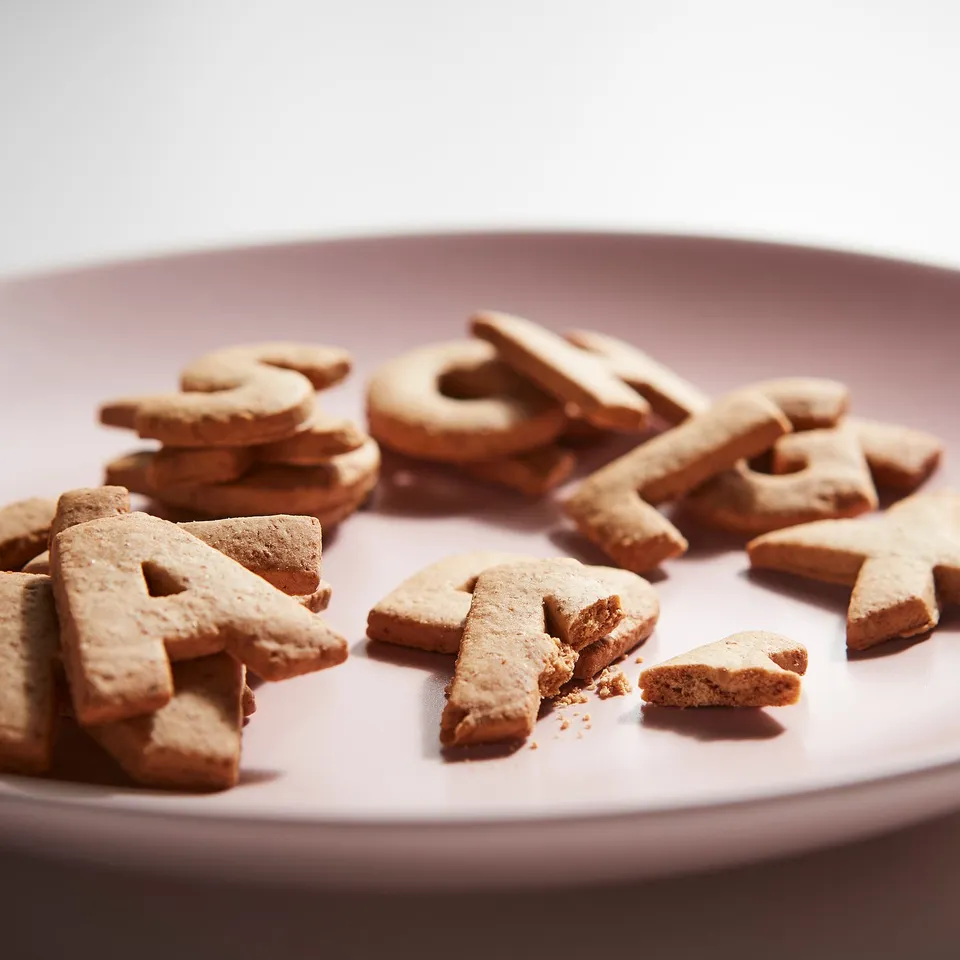 Light brown letter-shaped cookies spell KAFFEREP on a pink plate.