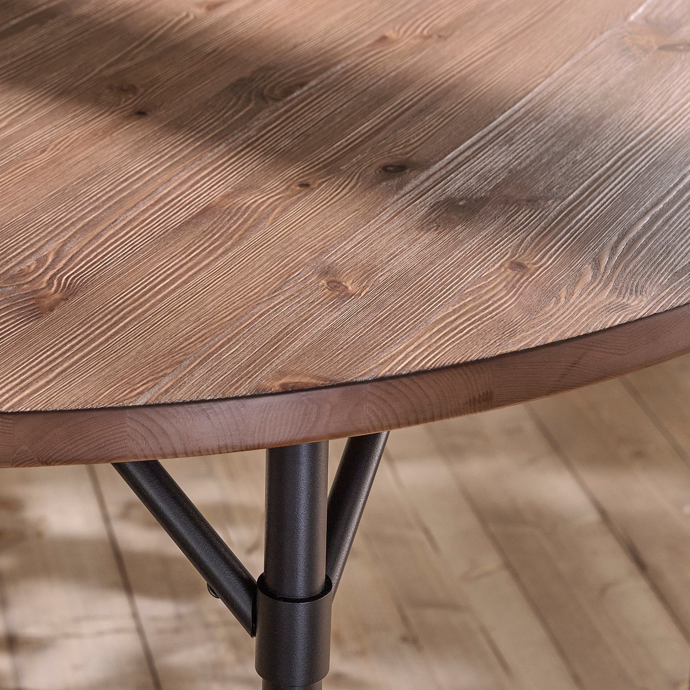 Rustic round wooden table with sturdy metal legs, showcasing quality craftsmanship and stability.