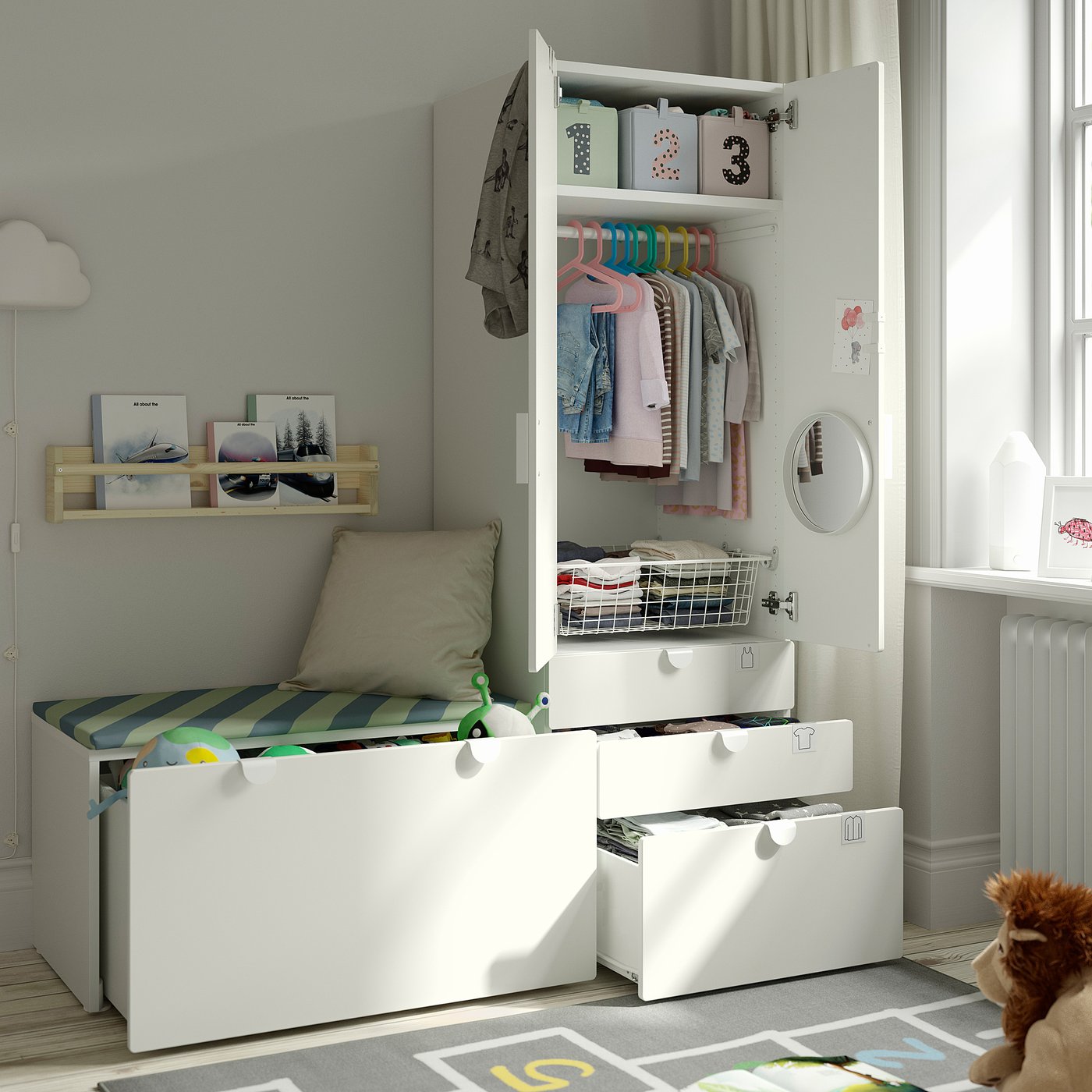 Cosy kids room with white storage unit: open wardrobe shows hangers, shelves, and drawers. Bench with cushions offers seating.