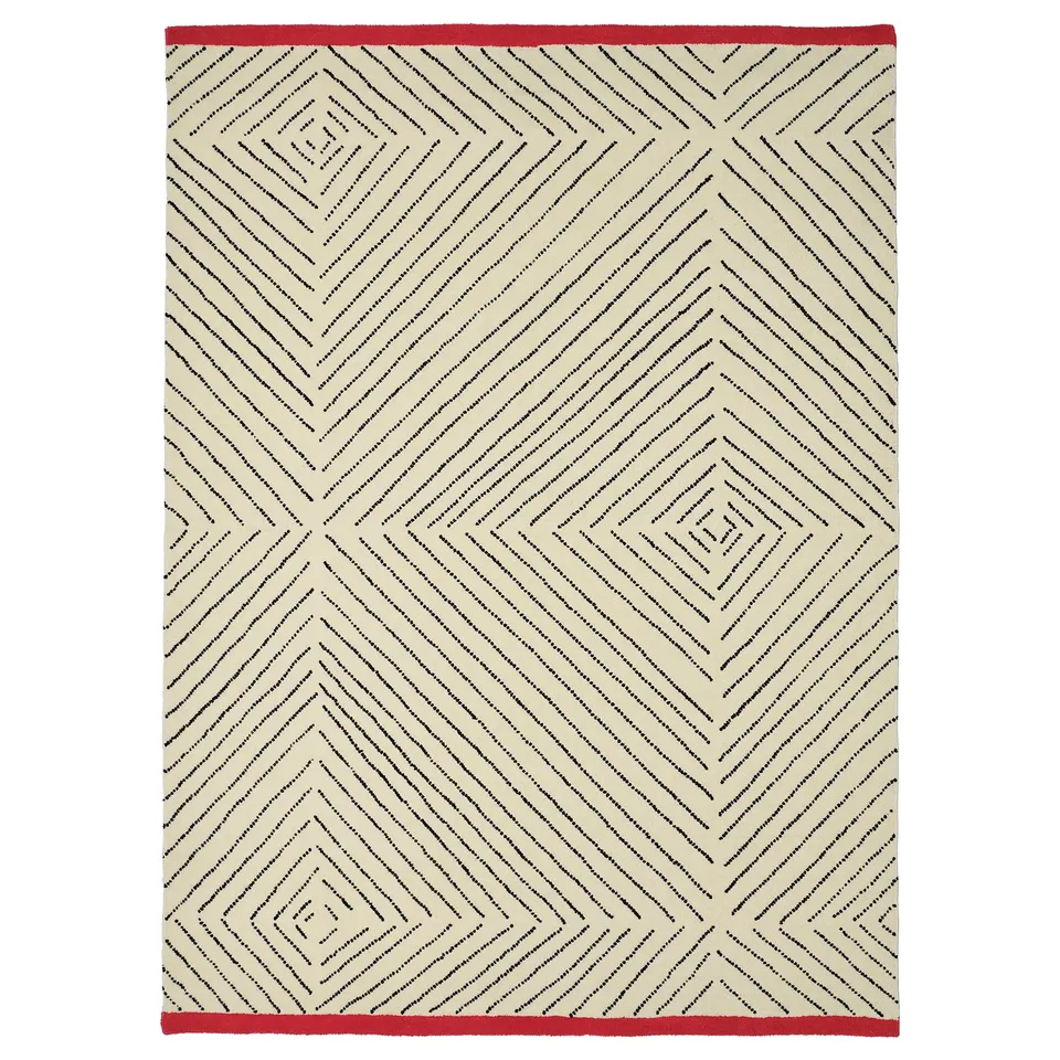 A rectangular rug called UNDERVISNING, featuring a diamond pattern with red edges, crafted from wool and cotton, with a soft, low pile surface.