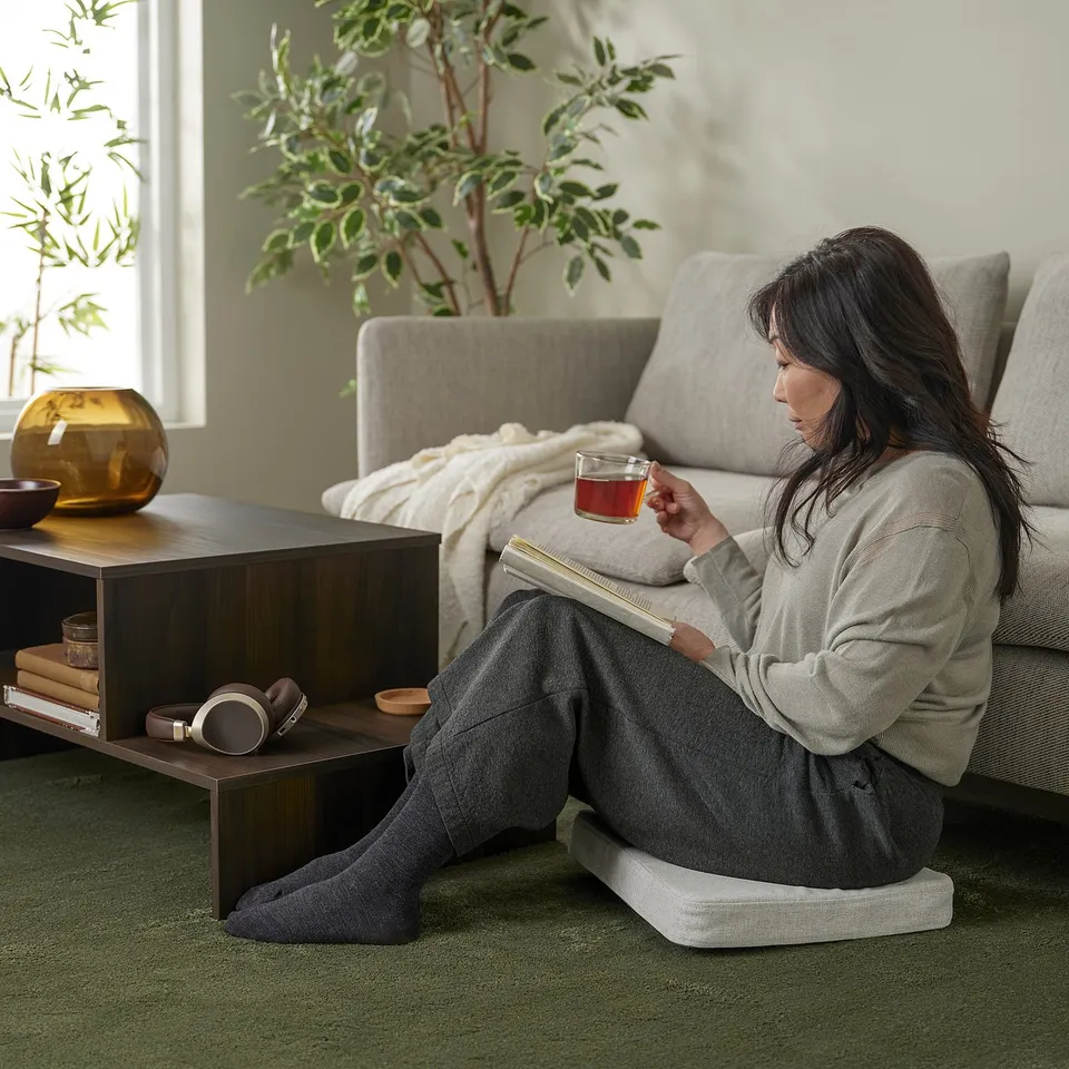 Person reads on rug with tea in cosy living room. Or person reads on comfy rug with tea in cosy living room.