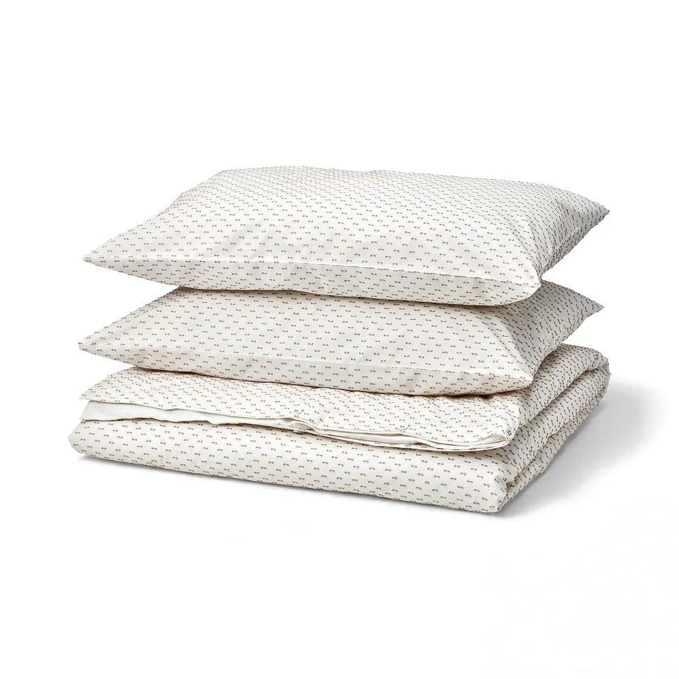 Stack of three white BANDKNIPPE cotton duvet covers with beige patterned dots.
