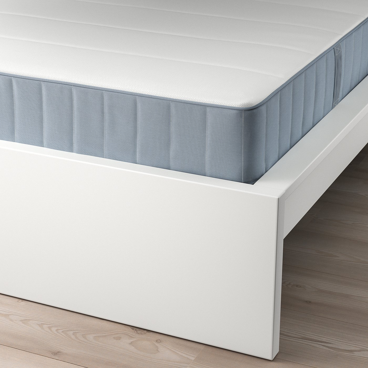 Corner of a white MALM bed frame with a light grey quilted mattress. Shows supportive slats and adjustable design.