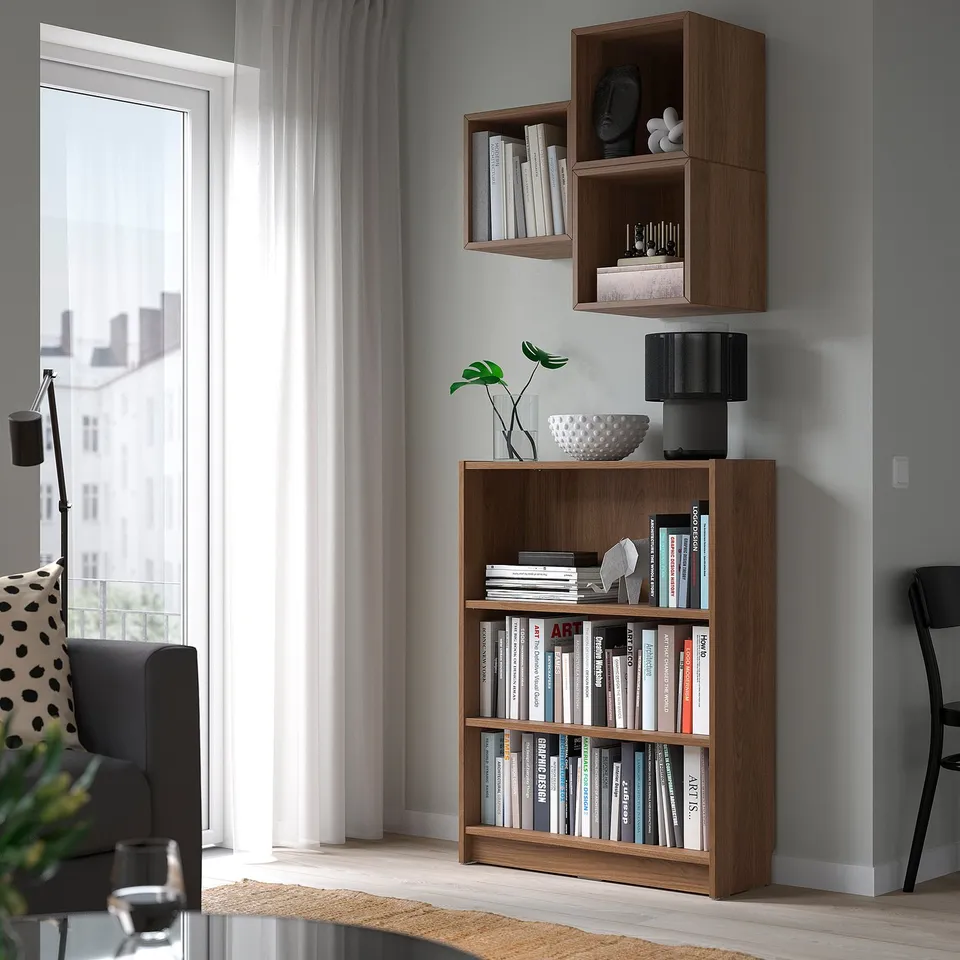 Modern living room with BILLY bookcase, books, lamp, plant, bowl, couch, chair, window.