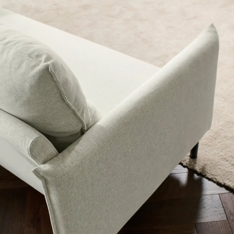 Light grey sofa with high back, soft cushions, and dark wood legs.