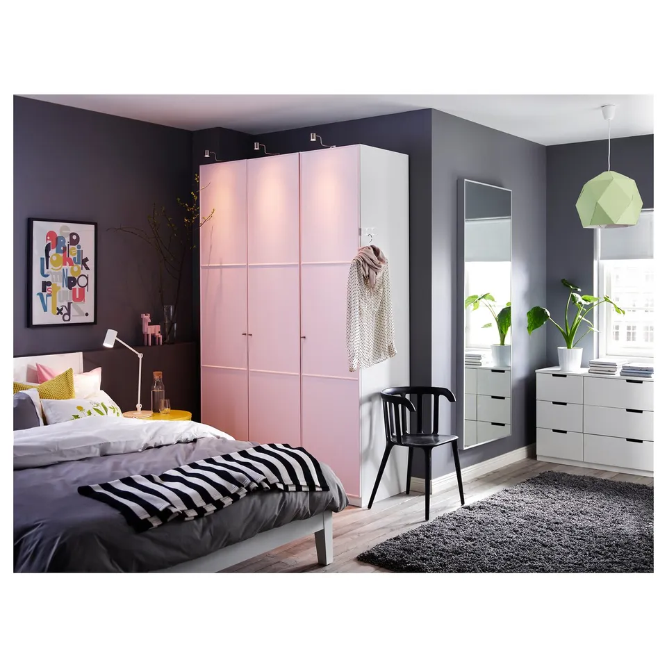 Modern bedroom with light pink closet, black and white bedding, large mirror, black rug, and green lamp shade.