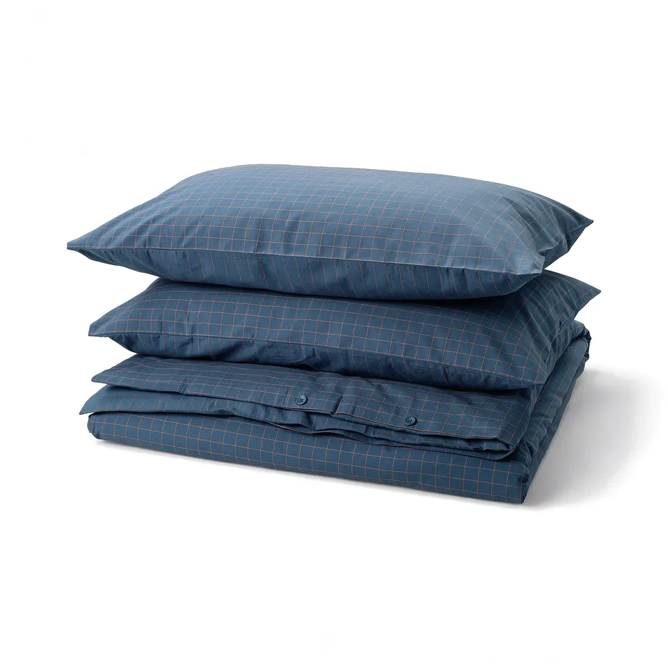 Three folded blue chequered pillows and blanket neatly stacked, dark blue with stitched check pattern.