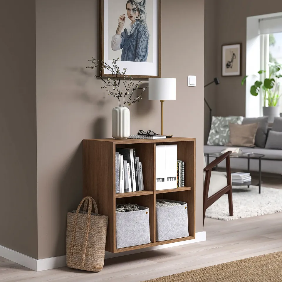 Modern living room with ekét unit, books, lamp, sofa, pillows, and rug.
