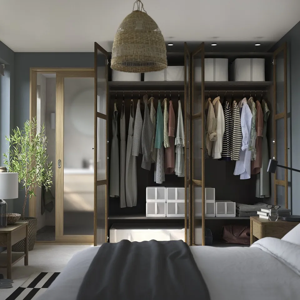 Open wardrobe with clothes, organised on hangers, shelves with boxes, and a pendant light. Bed partially visible.
