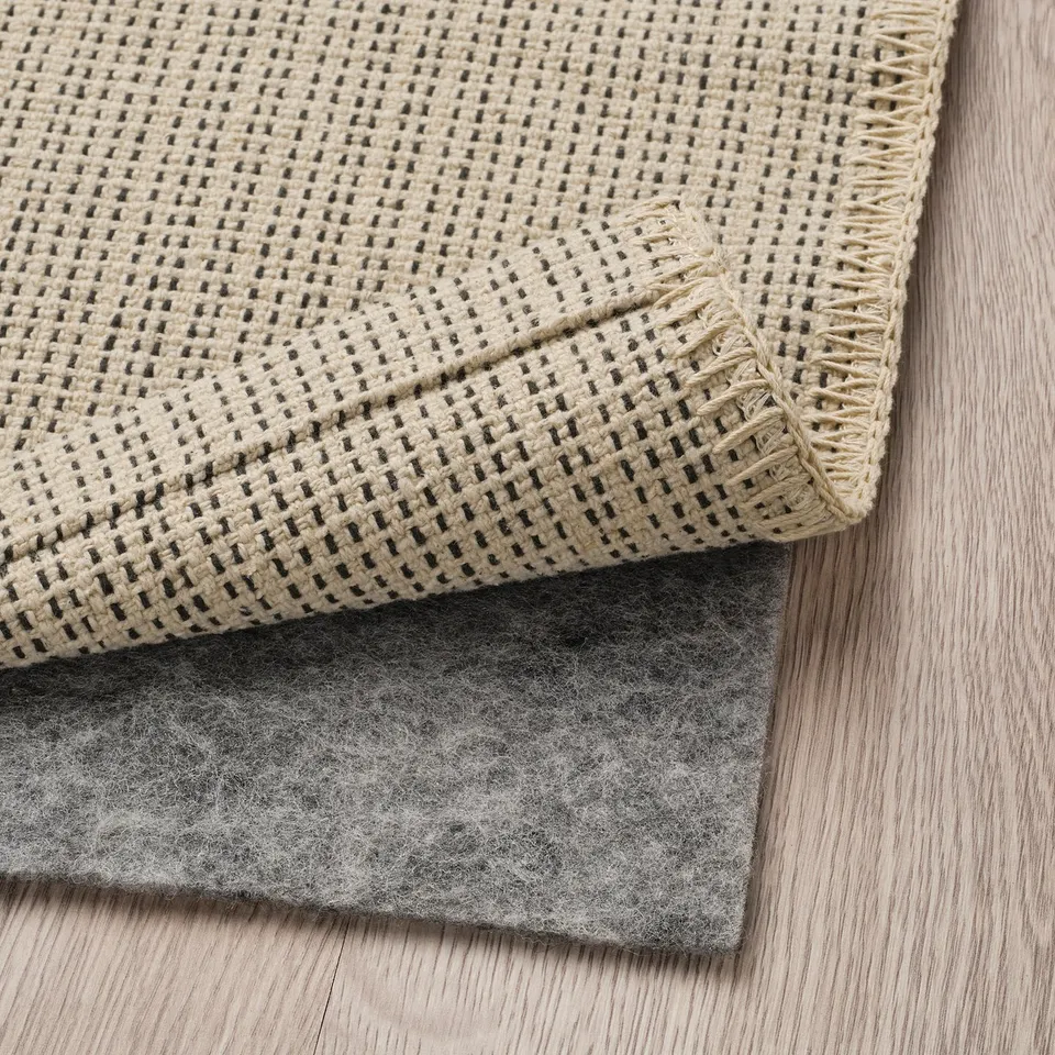 Flatwoven rug on wooden floor with anti-slip mat underneath.
