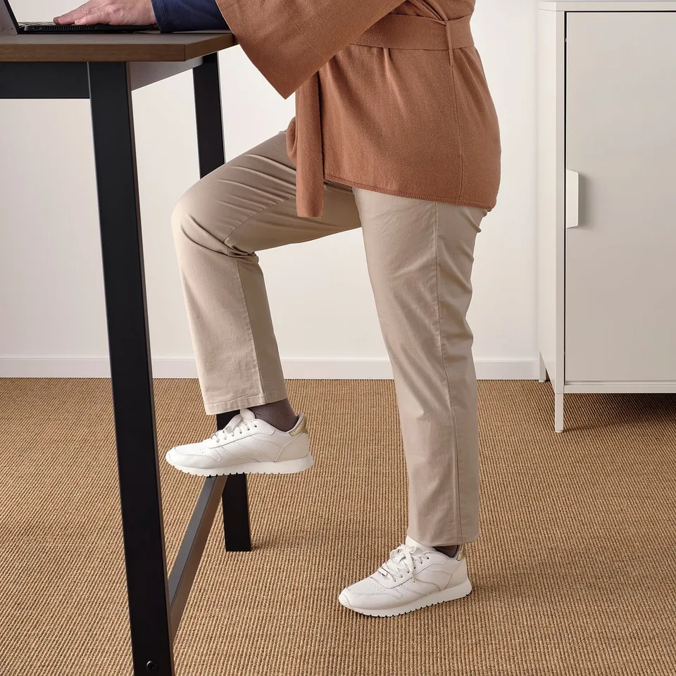Person using standing desk with footrest.