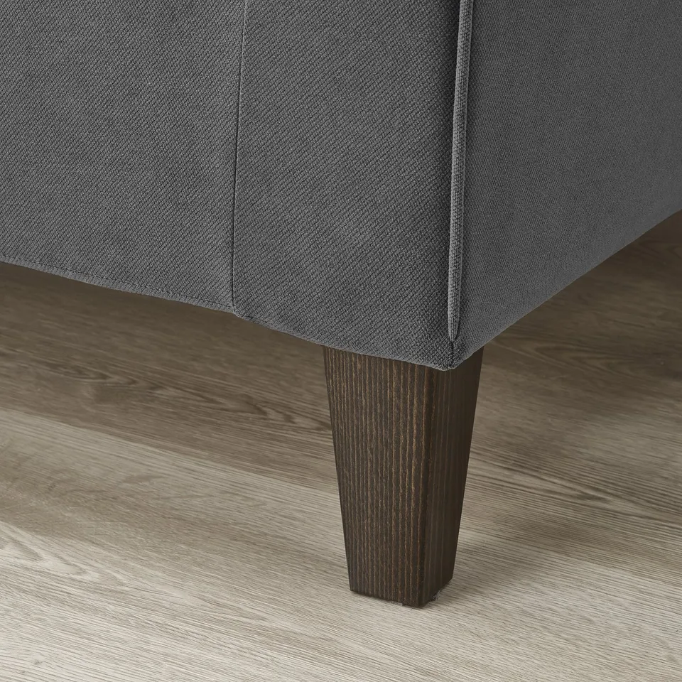 Close-up of a grey EKHOLMA sofas dark wooden leg, showcasing its sturdy and stylish design.