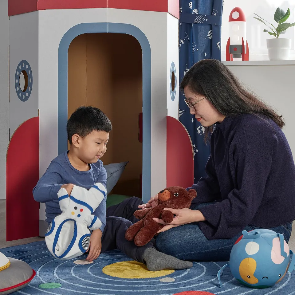 Person & child playing with teddy bears in colourful playroom.