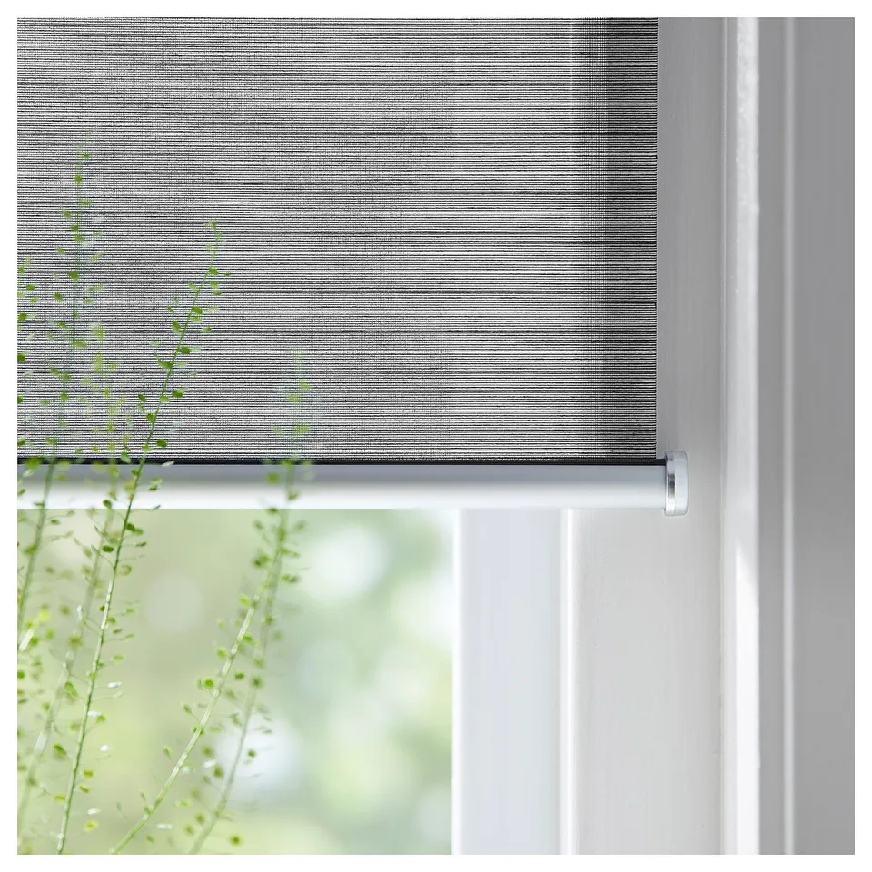 Modern grey roller blind with soft closing, mounted on white window frame.
