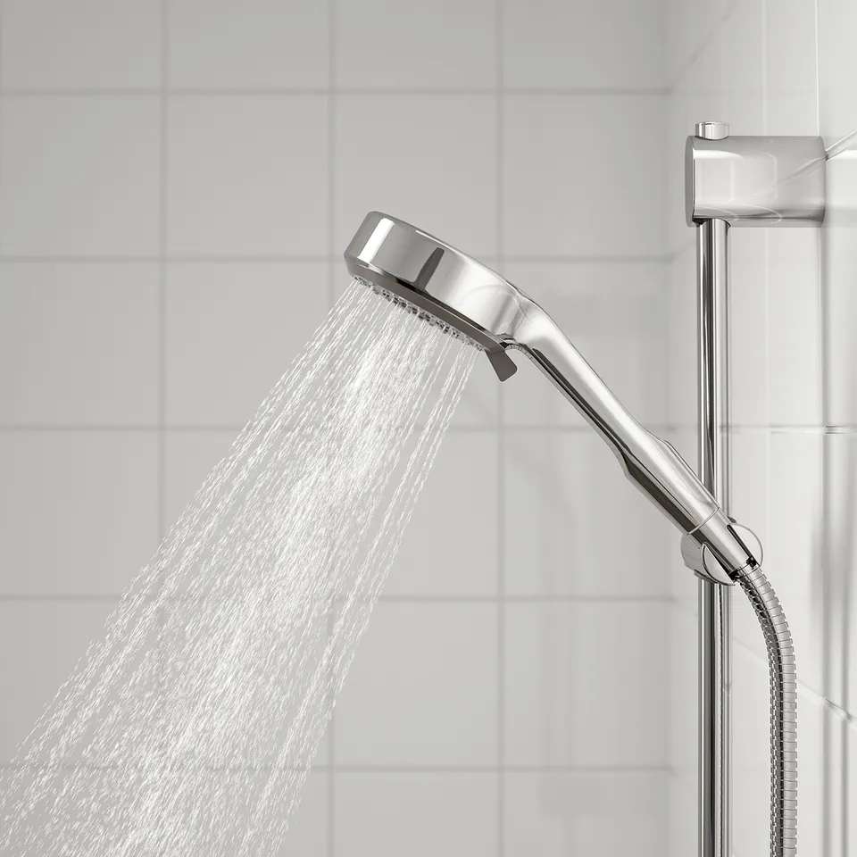 A chrome-plated shower head displays a full spray, producing a wide and even water coverage.