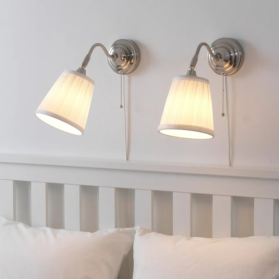 Two wall lamps above bed, light on.