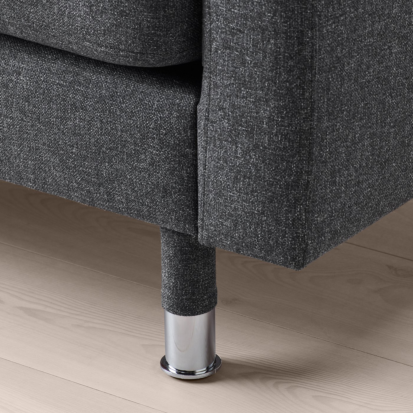 Close-up of a modern, sleek sofa with dark fabric and polished metal legs on a wooden floor.