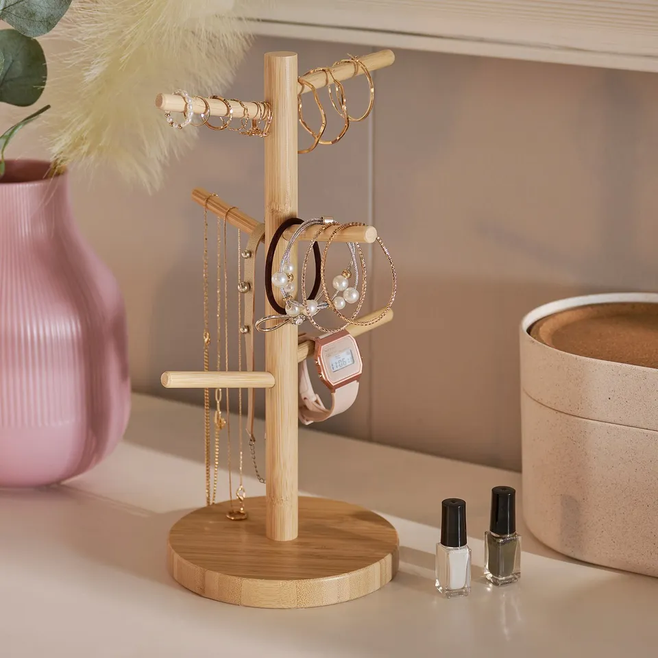 Bamboo jewellery stand with necklaces, bracelets, rings, and watch.