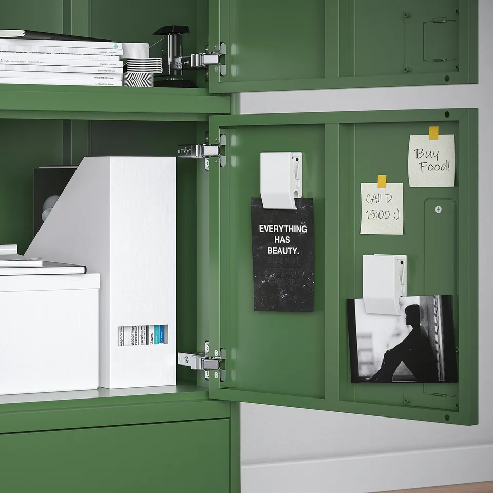 Green metal cabinet with open door showing storage and notes on magnet board.