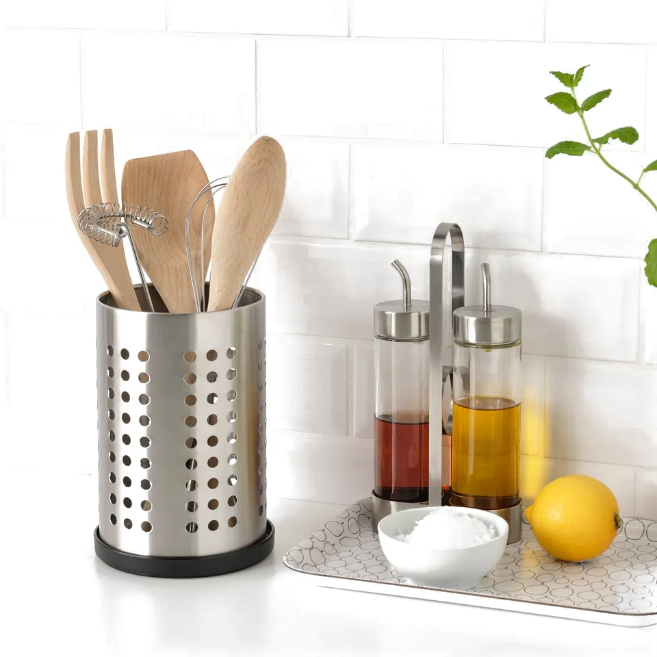Countertop with silver utensil holder, glass oil dispensers, lemon, bowl, and plant. Tray holds bowl under dispensers.