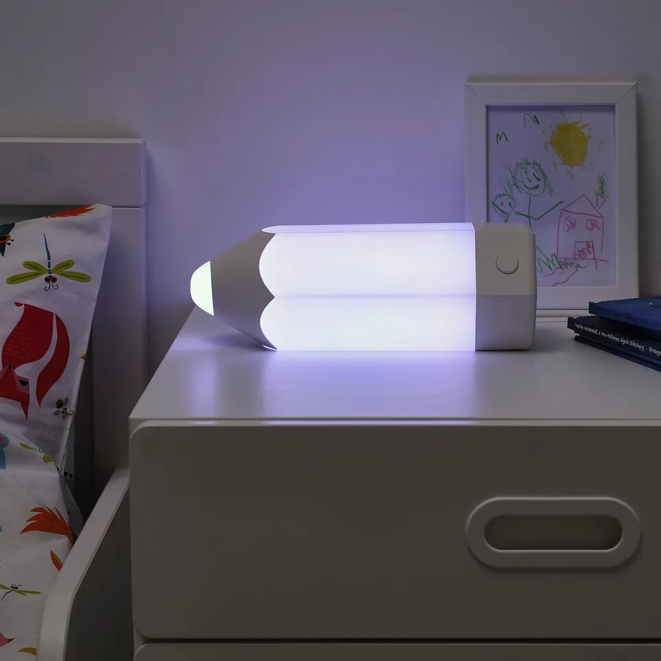 Modern kids lamp on a drawer, emitting soft light from a stylish, adjustable design, ideal for childs room.