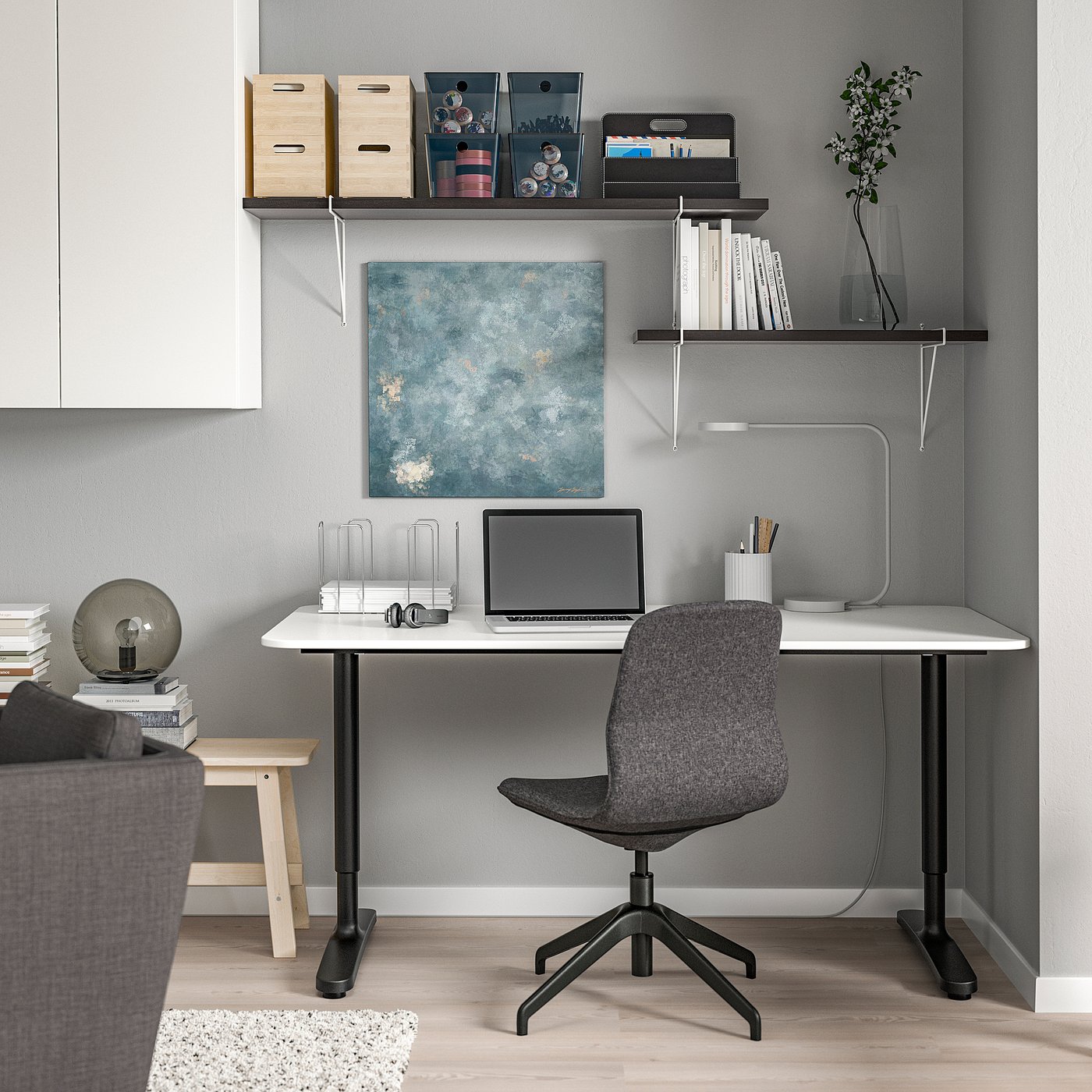 Modern home office with white desk, grey chair, shelves, and artwork.