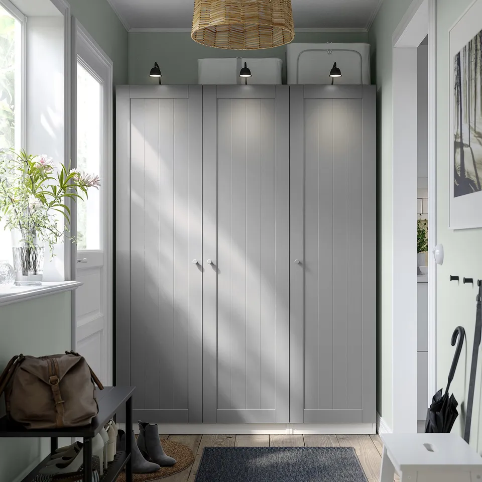 Grey PAX wardrobe beside window, bench with bag, vase of flowers.