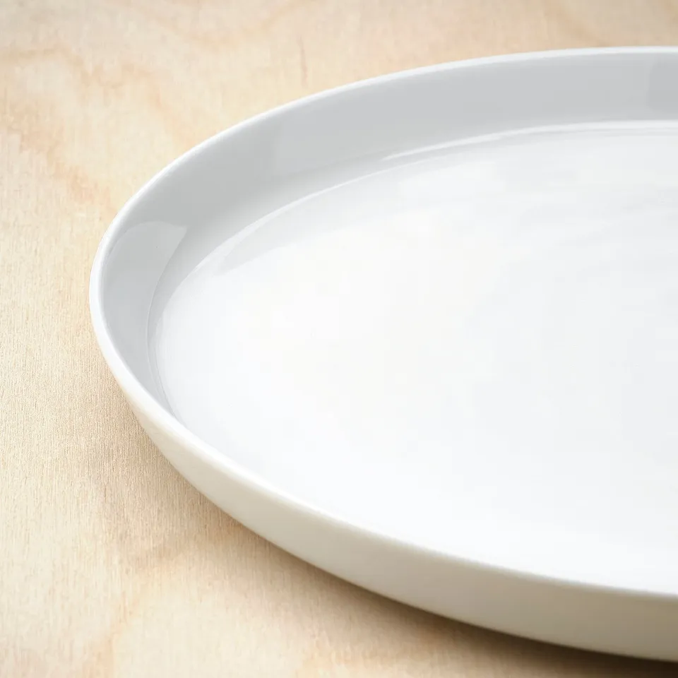 Clean, smooth, white porcelain plate on a wooden surface. Simple, modern design.
