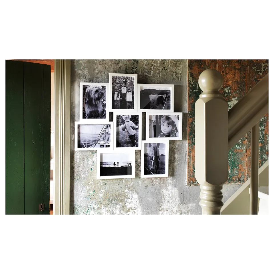 White VÄXBO photo frame collage with 8 photos on distressed wall near staircase.