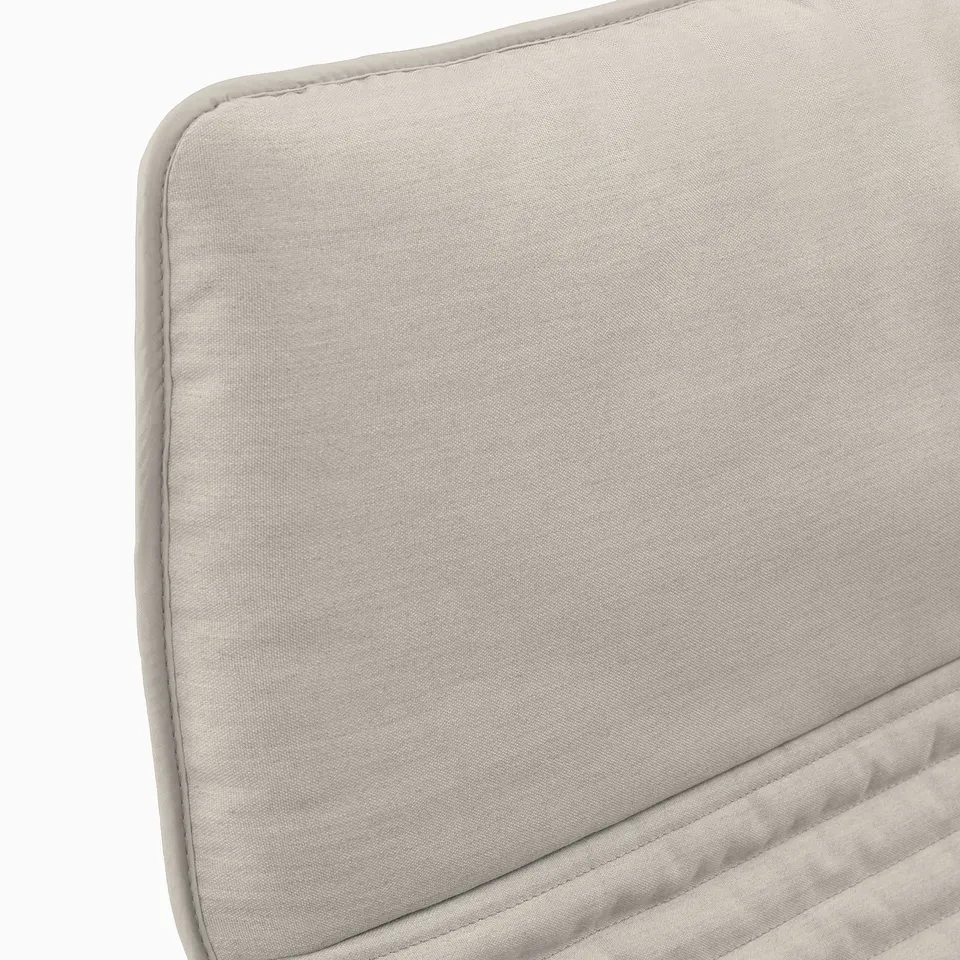 A close-up of a beige fabric armchair cushion. Highlights the smooth texture and neat stitching of the high-quality material.