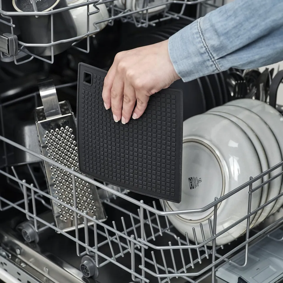 Placing silicone mat in dishwasher.