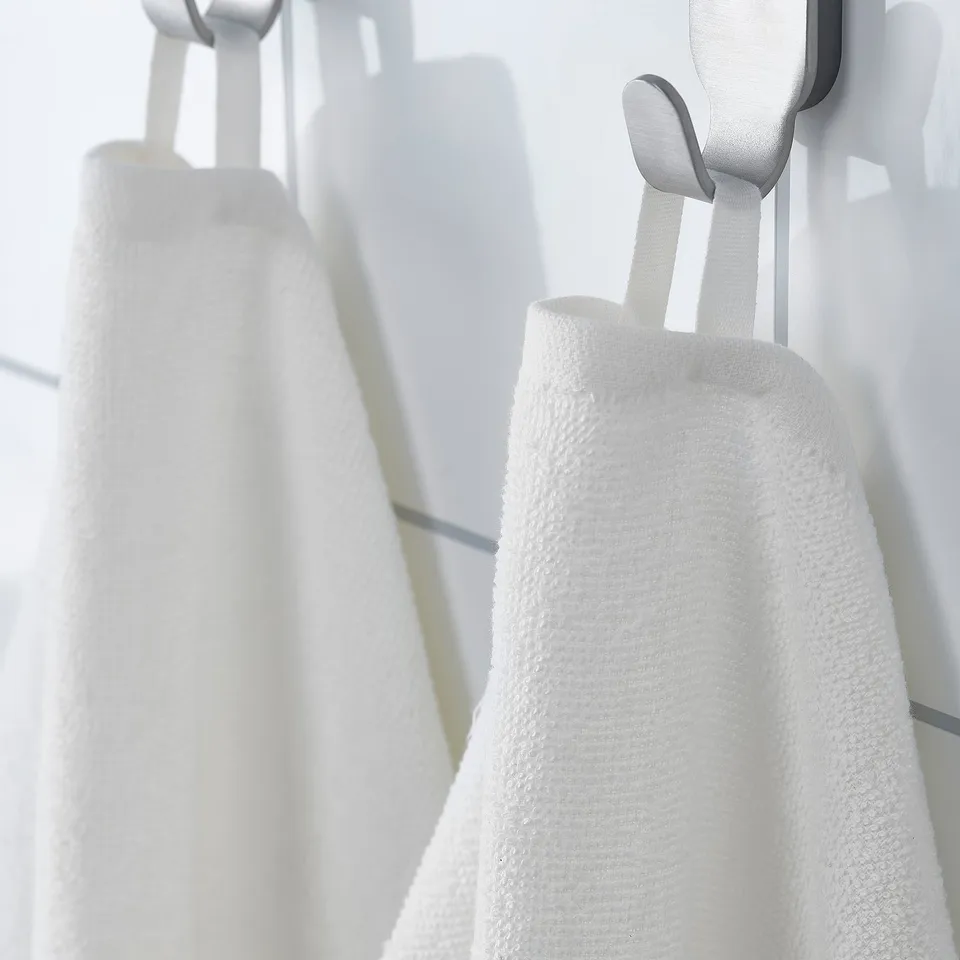 Two white towels hang neatly on hooks. The larger towel folds compactly, ideal for travel or gym use.