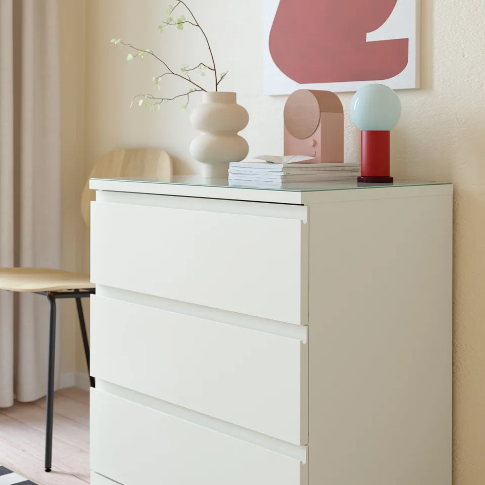 Modern chest with glass top for protection, displaying decor and photos.