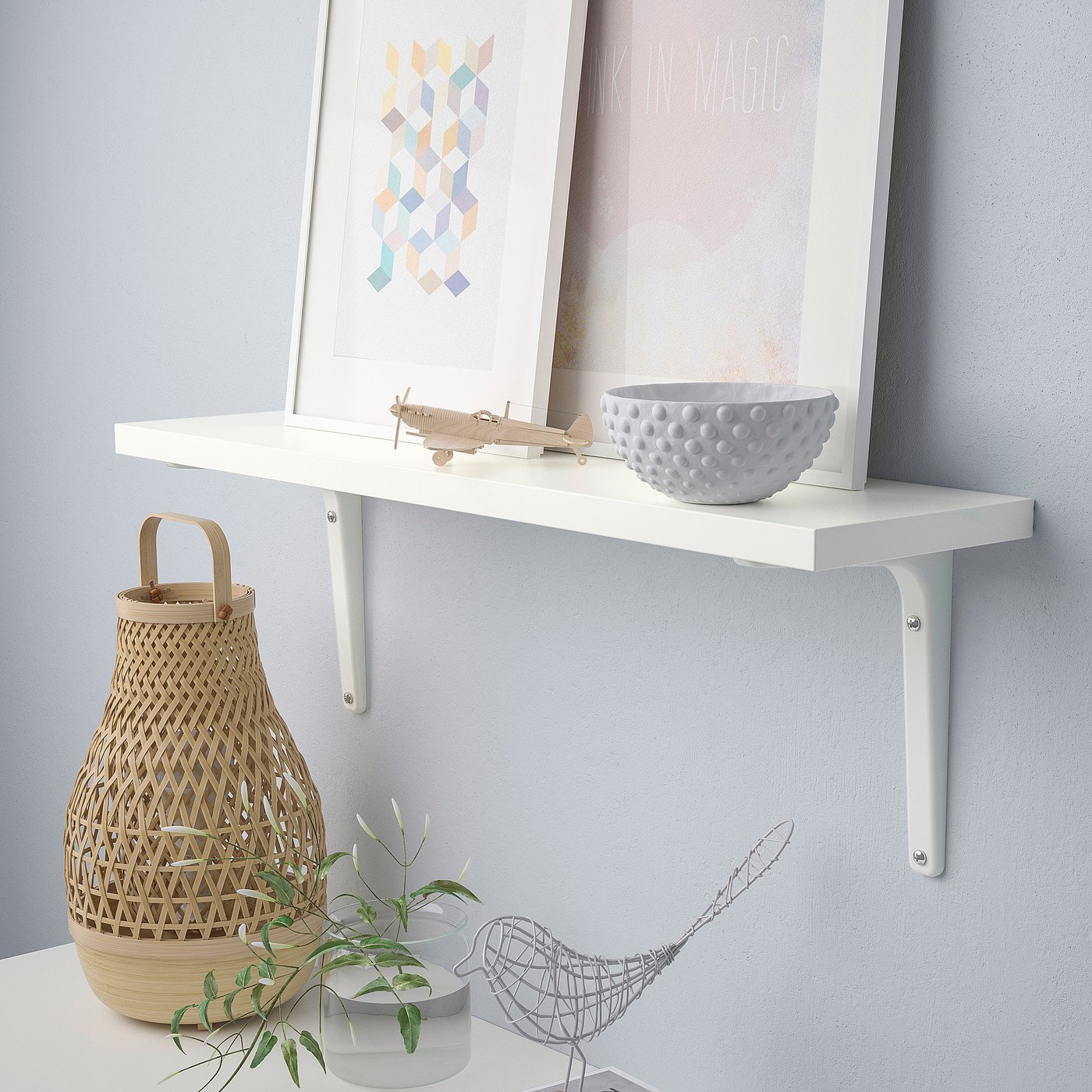 White wall shelf holds various decorative items like a bowl, plane model, and basket.