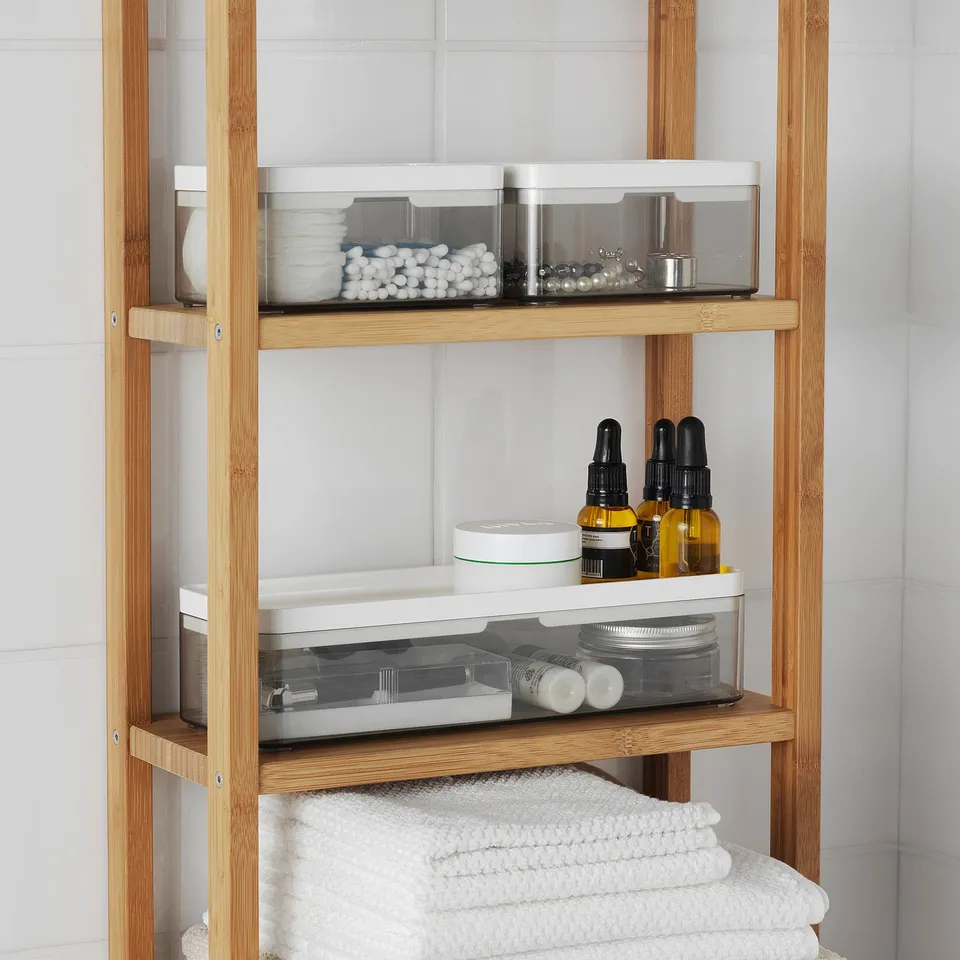 Wooden bathroom shelf with transparent storage bins and neatly folded towels.