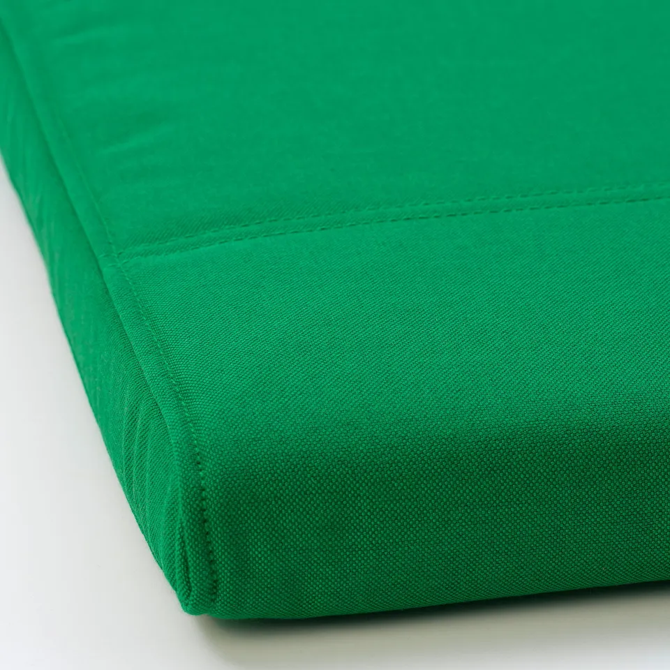 A close-up of a bright green fabric, showcasing its smooth texture and neat stitching. High quality and neatly sewn.