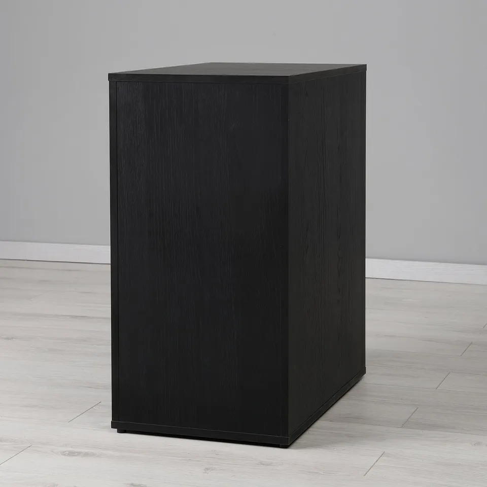 Black square storage unit on wooden floor with complete back finish for central placement.