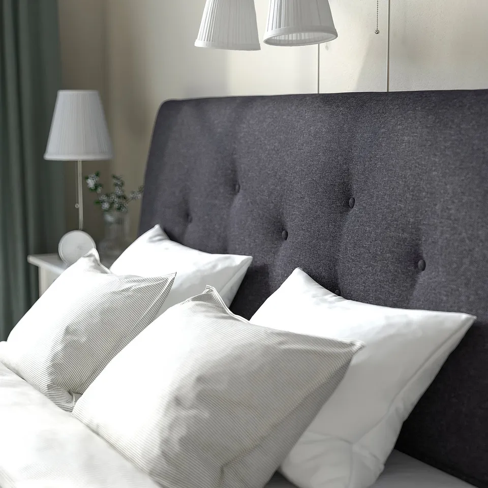 Bed with dark grey headboard, white pillows, under-bed storage, two lamps.