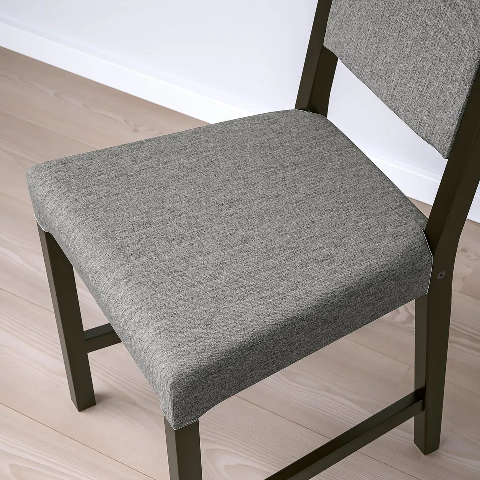 Modern upholstered chair, black wood frame. Upholstery has a textured, grey fabric. Seat and backrest are cushioned for comfort. Sturdy, clean design.