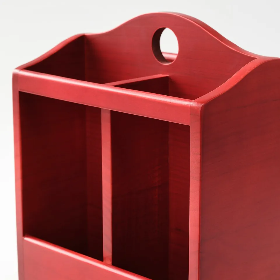 Red wooden knife block, painted, with handle and compartments for kitchen utensils.