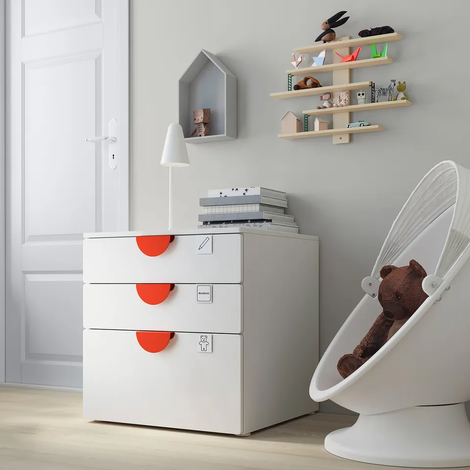Childrens playroom with white SMÅSTAD chest, shelves, lamp, and teddy bear.
