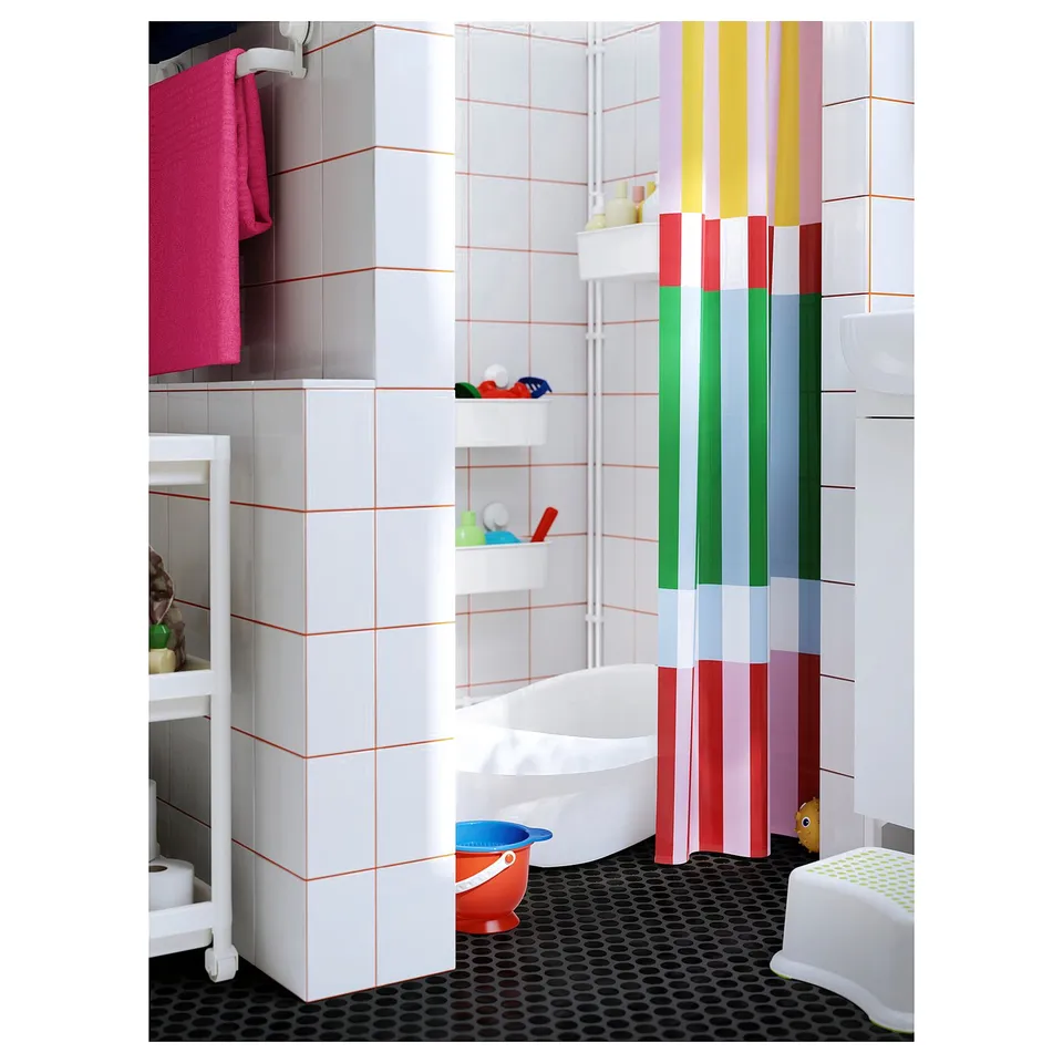 Bright bathroom with multicoloured stripe shower curtain, white bathtub, toilet, and black hexagon tile floor.