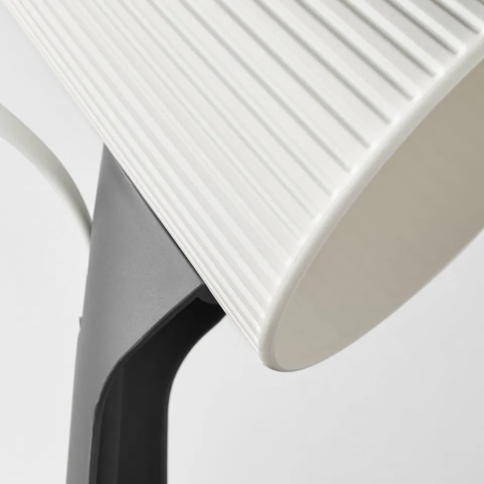 Close-up of modern, minimalist lamp with sleek, curved design and textured surface.