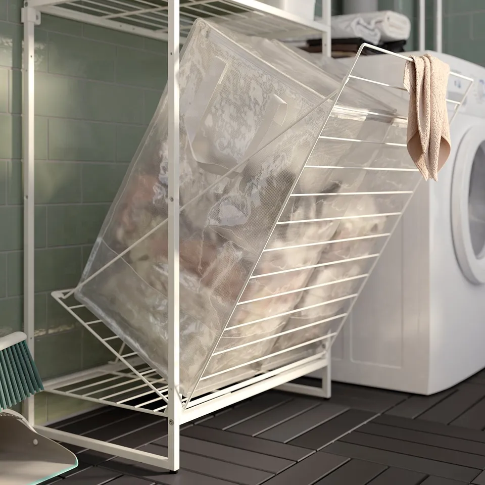 A white JOSTEIN storage system with a mesh bag and a beech-colored towel, ideal for balconies or laundry rooms due to its moisture-resistant design.