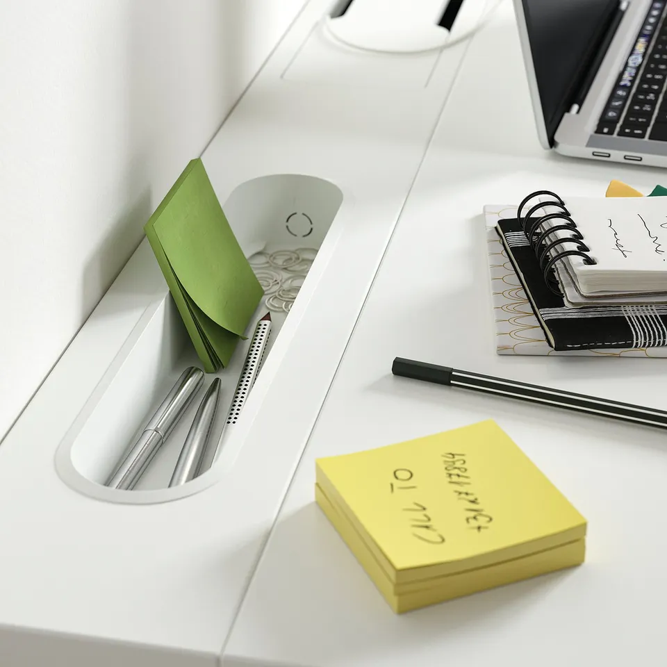 Desk with compartments, pens, and sticky notes. Aesthetic office setup with green and yellow sticky notes, pens, notebooks, and laptop.